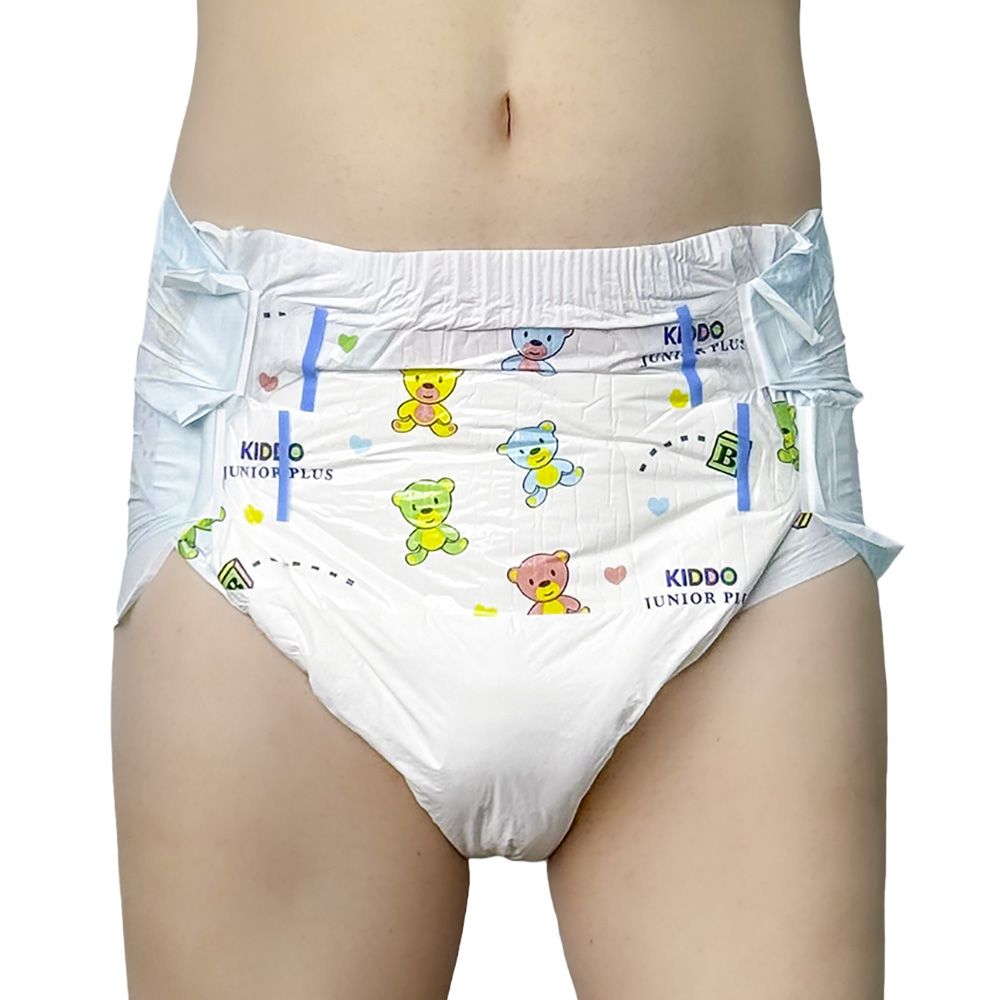 Ein Windelprodukt mit bunten Bärenmotiven, das an einer Person getragen wird. Die Windel hat seitliche Klettverschlüsse und eine elastische Taille, vor neutralem Hintergrund.