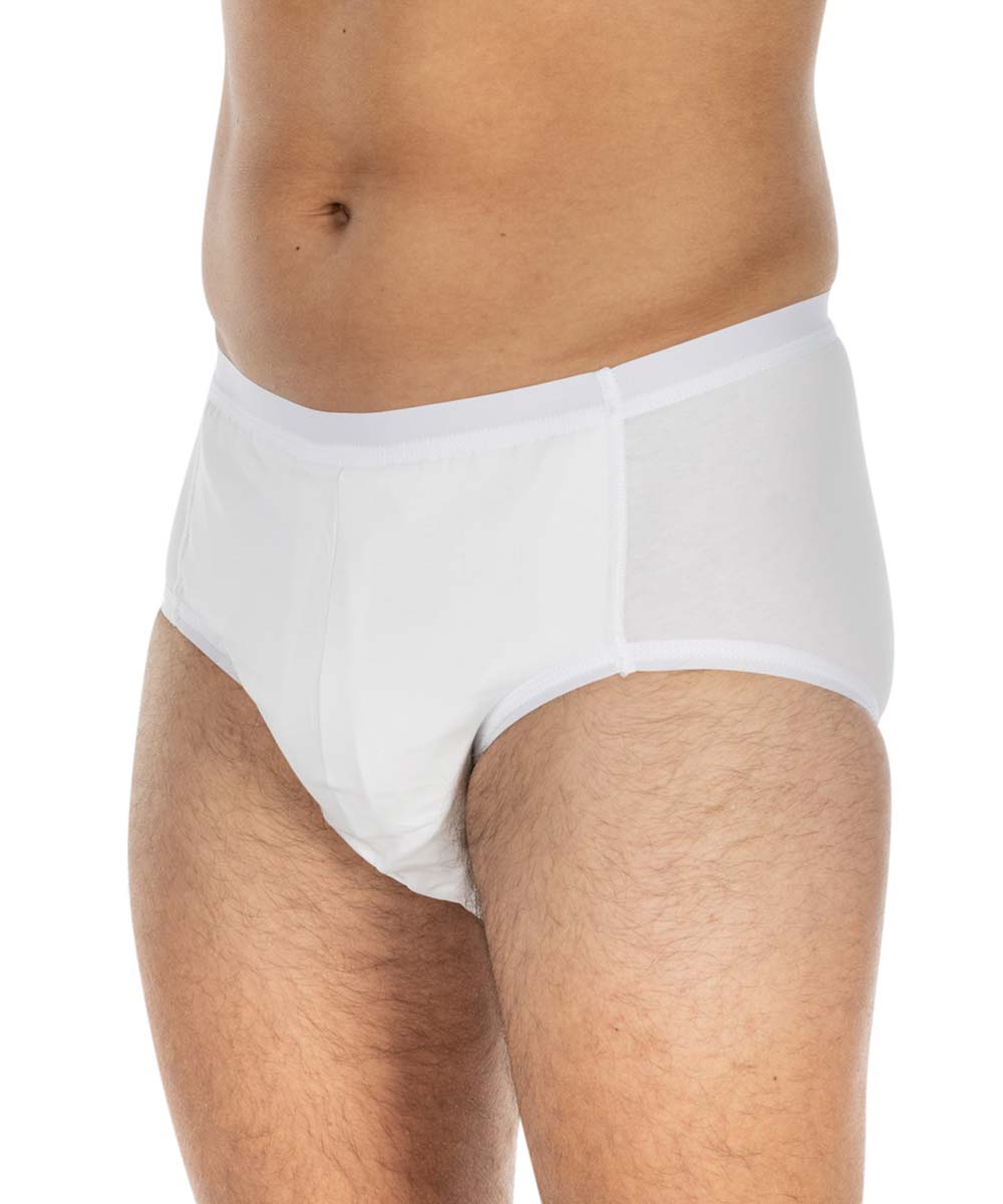 Ein weißer, elastischer Inkontinenzslip wird seitlich an einem männlichen Körper präsentiert, der ein dunkelhaariger und unrasierter Bauch sowie Beine sichtbar hat. Der Hintergrund ist neutral und einfarbig.