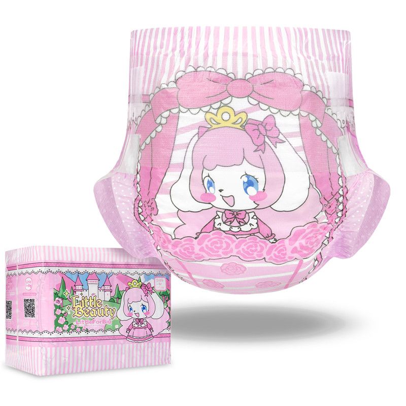 Ein rosa Windel mit einem Schwarz-Weiß-Comicfiguren-Design, das ein Mädchen mit Haaren und einer Krone zeigt. Daneben steht eine Verpackung mit dem Schriftzug -Little Beauty- und einer stilisierten Burg im Hintergrund.